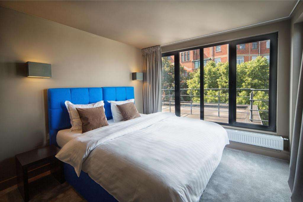 een slaapkamer met een groot bed en een groot raam bij Hotel The Neufchatel in Brussel