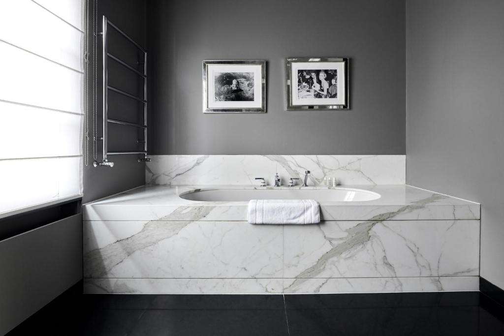 een witte badkamer met een bad en een wastafel bij Hotel Odette en Ville in Brussel