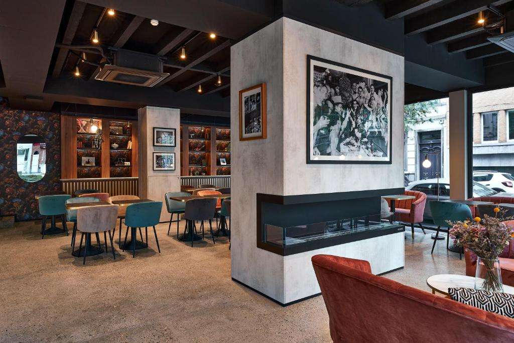 een restaurant met een open haard en tafels en stoelen bij The Scott Hotel Brussels in Brussel
