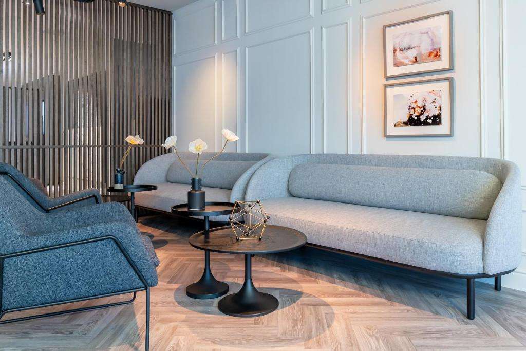 een woonkamer met een blauwe bank en twee tafels bij Pillows City Hotel Brussels Centre in Brussel