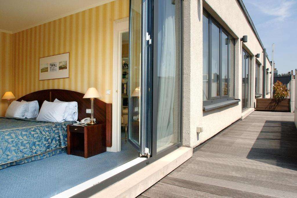 een hotelkamer met een bed en een balkon bij Hotel Le Châtelain in Brussel