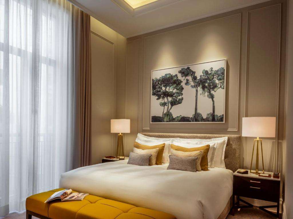 een slaapkamer met een groot wit bed met 2 lampen bij Corinthia Grand Hotel Astoria Brussels in Brussel