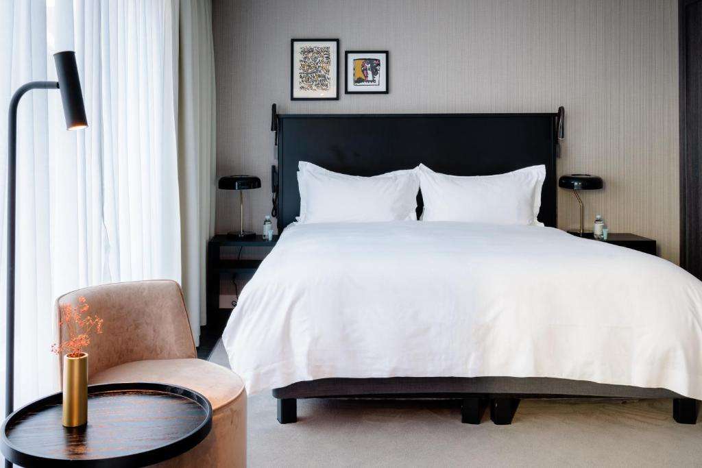 een slaapkamer met een groot wit bed en een stoel bij Pillows City Hotel Brussels Centre in Brussel